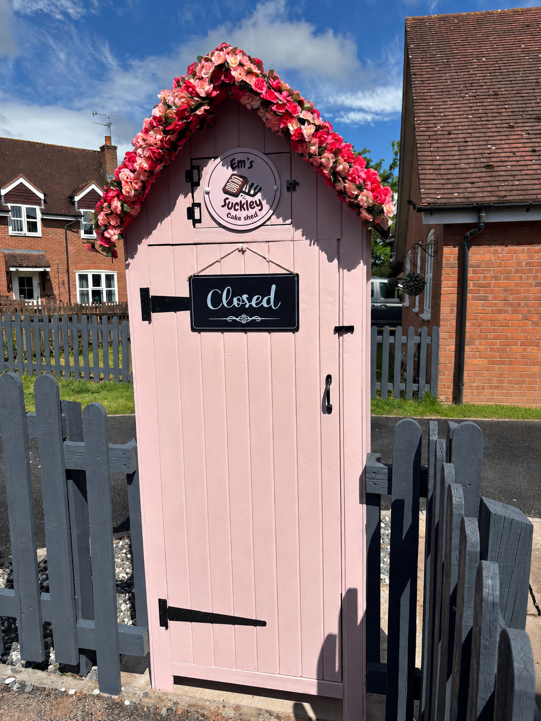 The pink Suckley Cake Shed with a floral arch over the door